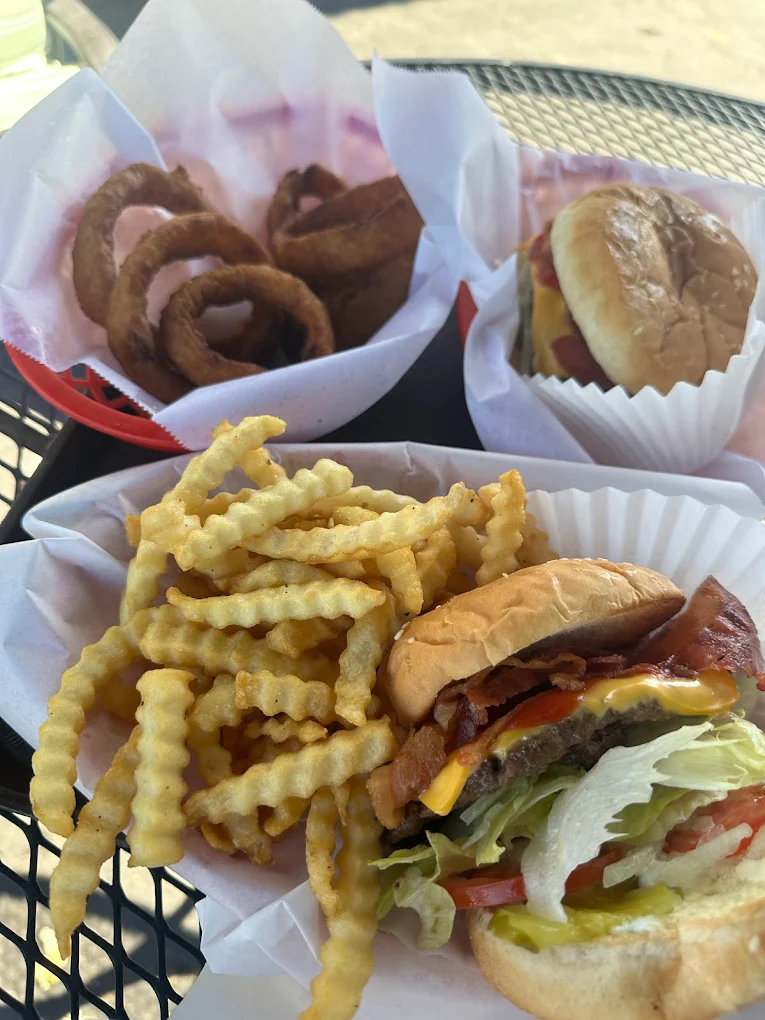 A thick juicy burger with two patties, cheese, lettuce and bacon, and a basket of fries.