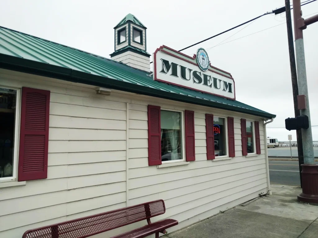 The outside of the Bandon Historical Society Museum. It's a white building, with red shutters and a green roof.