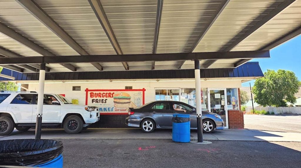 A black car and a white SUV in the covered drive through at Burger Bob's Drive-In, in Baker City, Oregon.