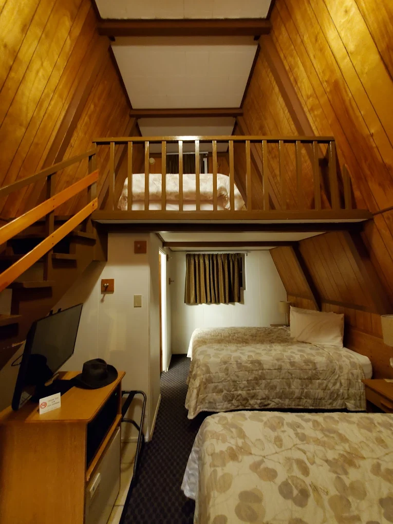 Inside one of the A-frame cabins at The Ranch Motel. Two beds and a TV are downstairs, and another bed is up in the loft.