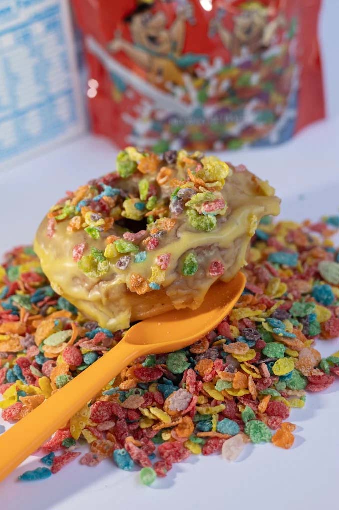 A donut with colorful cereal on top.
