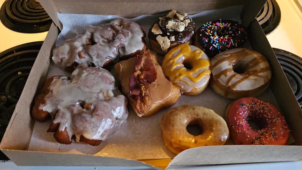 An assortment of colorful delicious fresh donuts in a box.