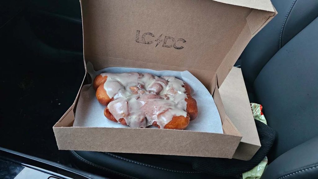 A huge fresh glazed donut in a box.