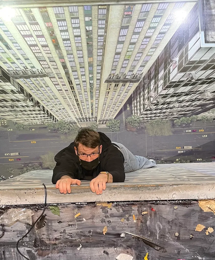 A man appears to be hanging from a skyscraper. It's a cool interactive exhibit where you can take your own photo.