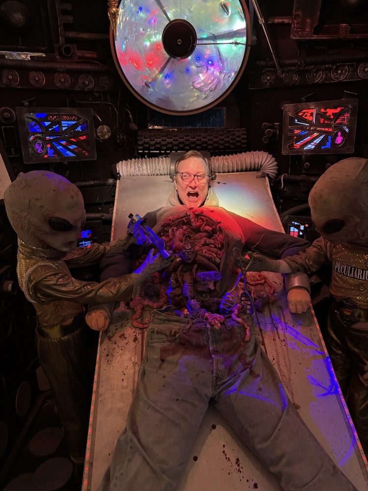 Aliens appear to cut open and operate on a visitor. It's an interactive photo display.