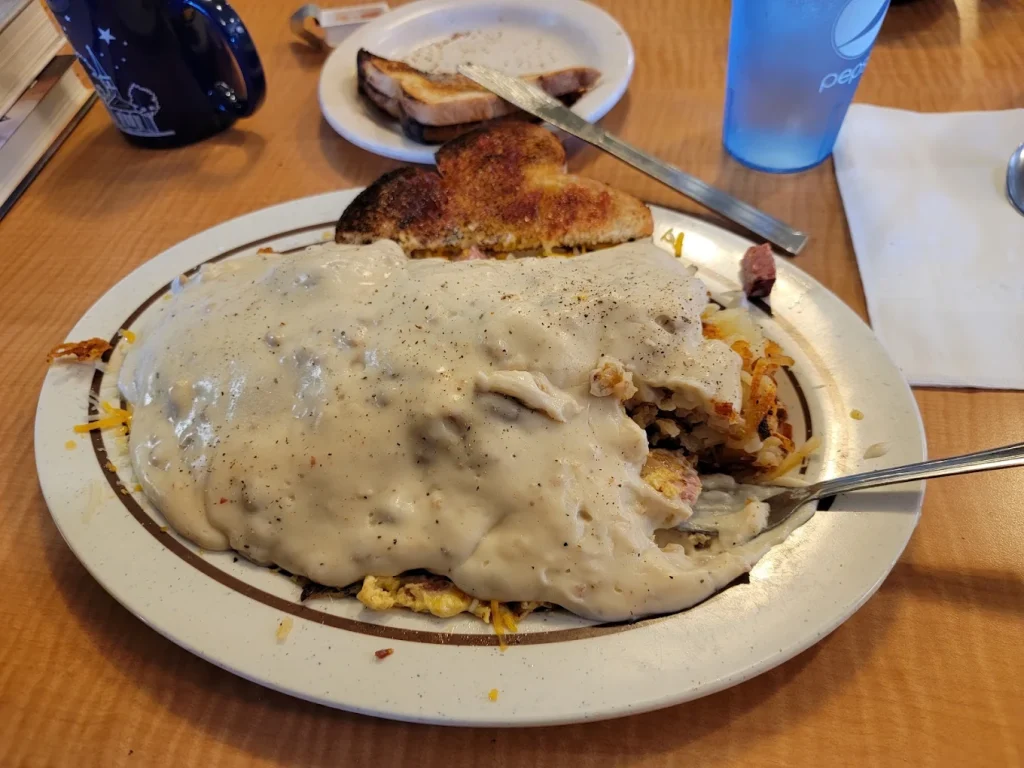 A plate of tasty looking breakfast food covered in thick sausage gravy.