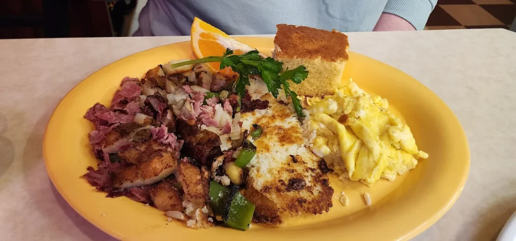 Corned beef and other delicious breakfast foods on a round yellow plate.