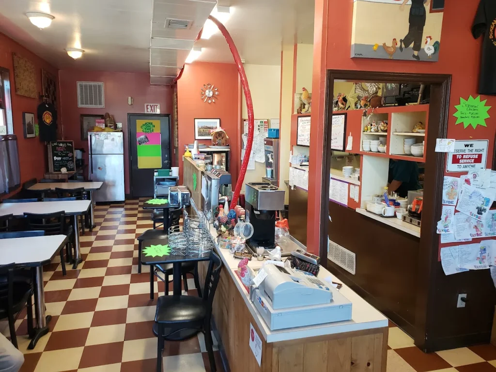 The inside of The Screamin' Chicken diner. There is a brown and white checkered floor, and several tables to sit at. It's a small diner.