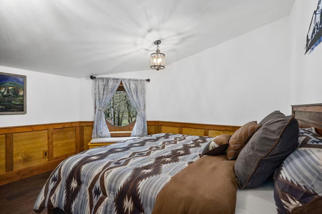 A bed in front of a round window.