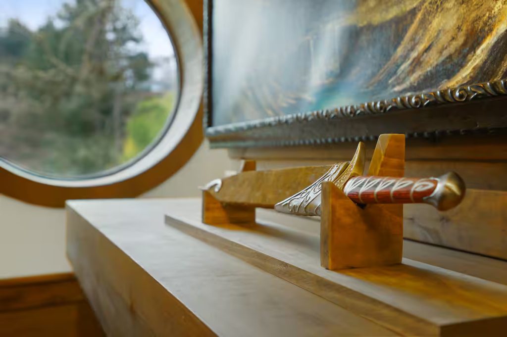 A recreation of a hobbit sword on the mantle in front of a round window.