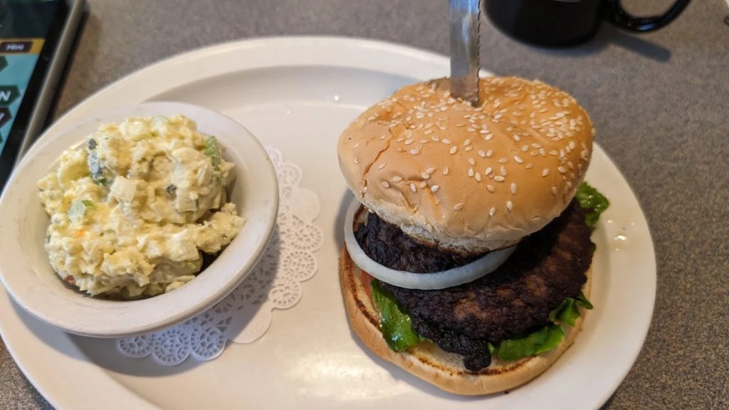 Classic cheeseburger on sesame bun with onion and side of creamy potato salad at The Berry Patch Restaurant Westport Oregon