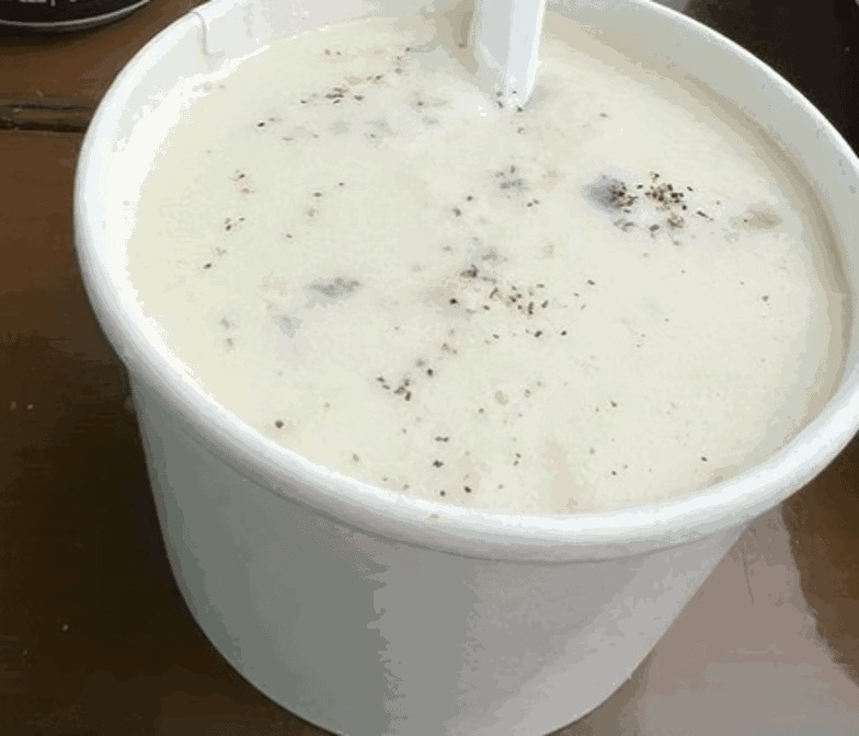 Cup of creamy clam chowder served at Bandon Bait in Bandon, Oregon, rich coastal seafood soup topped and ready to enjoy by the water.