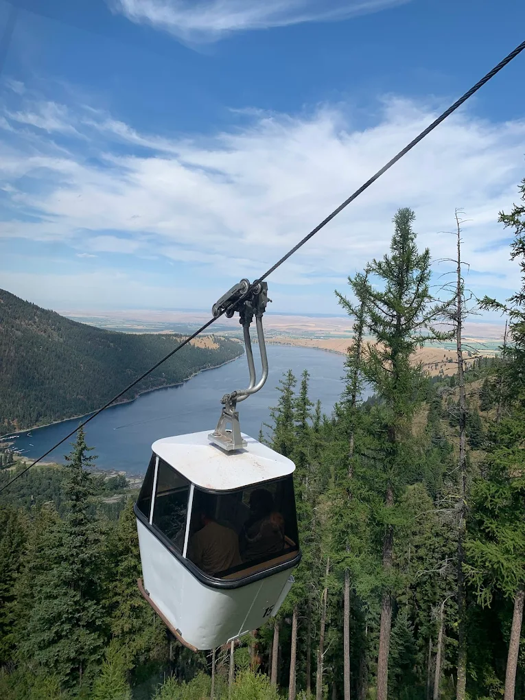 A gondola on the Wallowa Lake Tramway goes down the mountain. Wallowa lake sits in the distance.