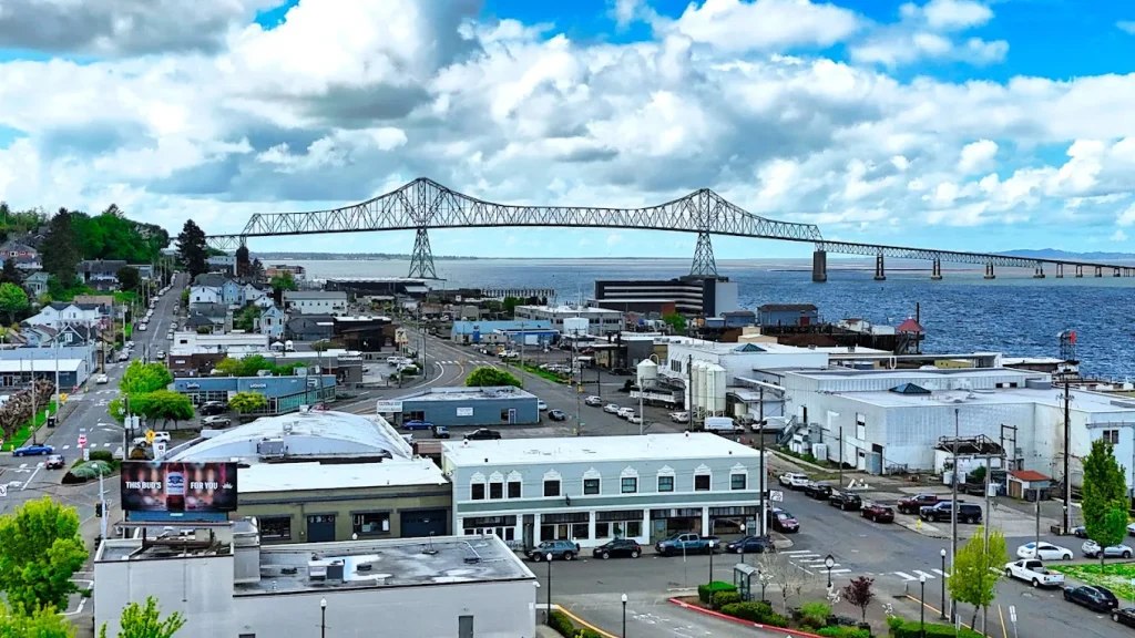 Businesses in Astoria with the iconic Astoria-Megler Bridge behind them, stretching over the river.