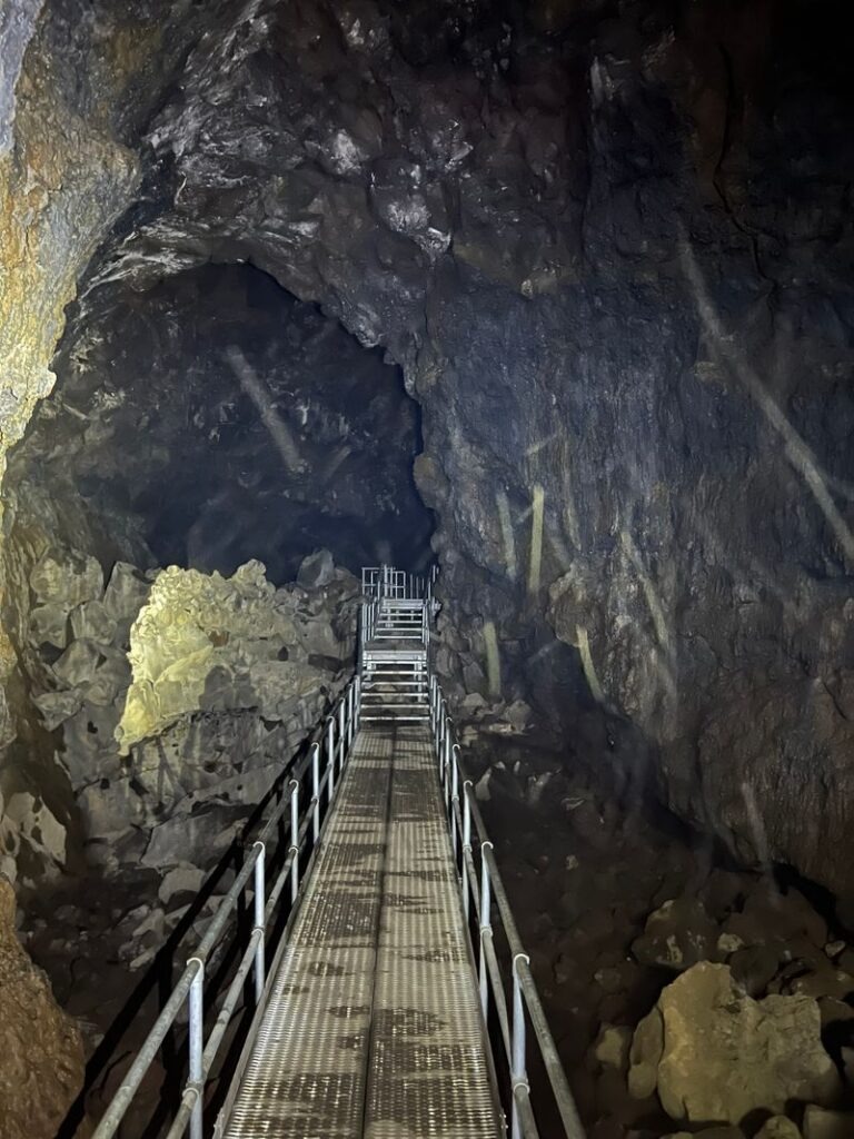 Metal walkway inside Lava River Cave showing rocky lava tube walls and underground hiking path in Oregon