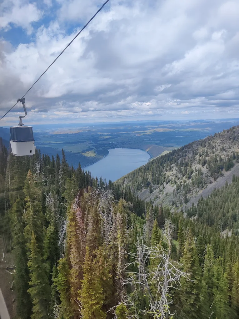 A gondola on the Wallowa Lake Tramway goes down the mountain. Wallowa lake sits in the distance.