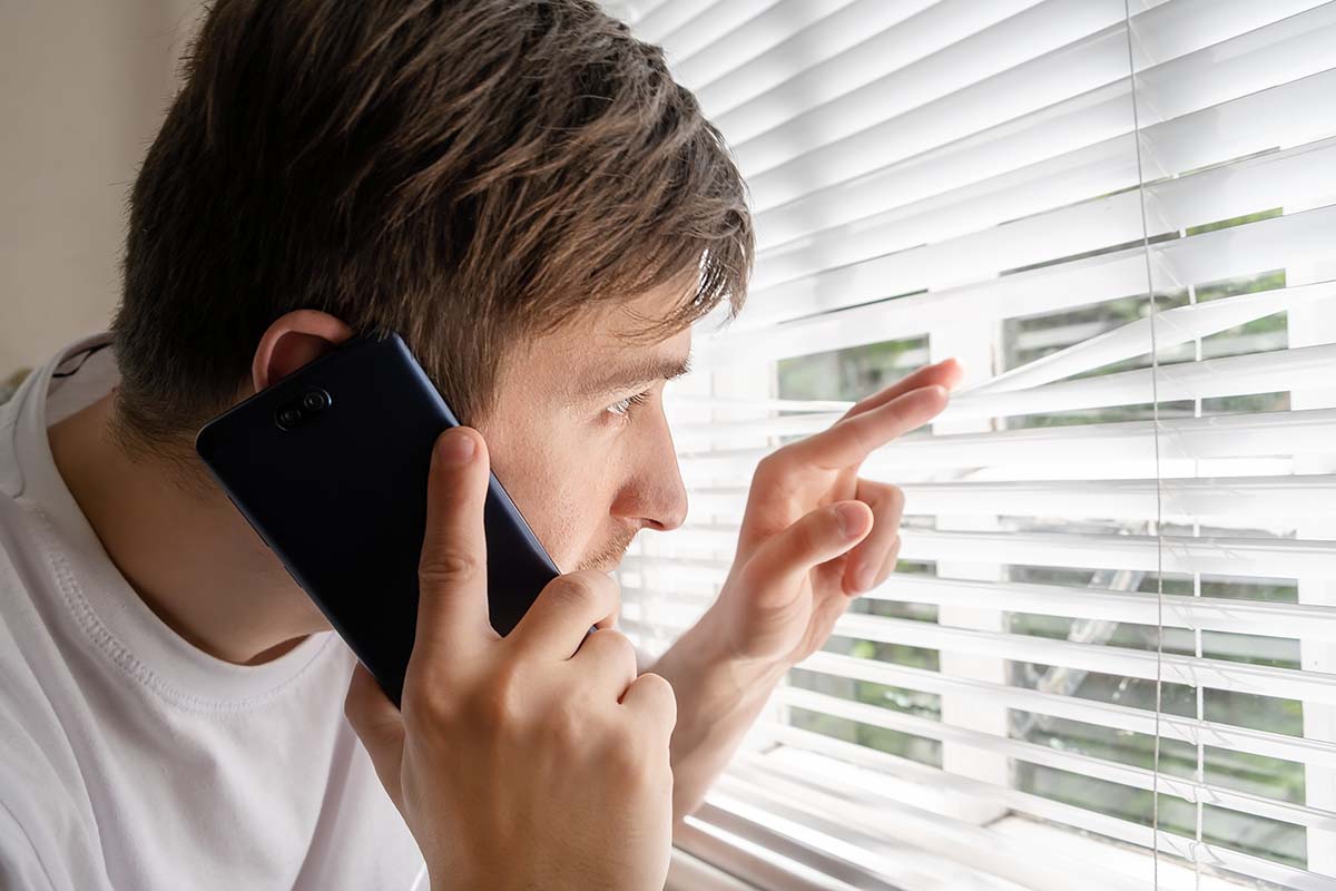 Young,Man,With,A,Phone,Is,Spying,Through,The,Jalousie