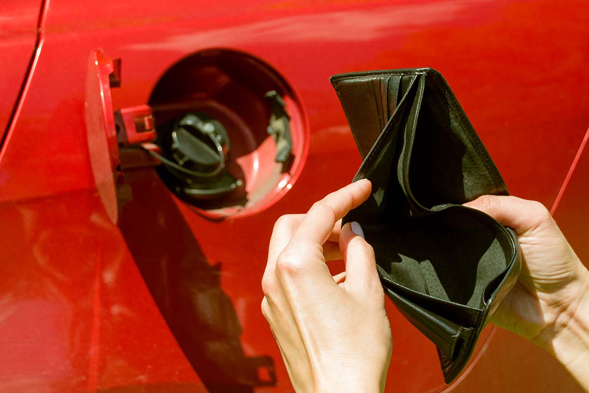 Empty,Wallet,On,The,Background,Of,The,Gas,Tank,Of empty wallet on the background of the gas tank of a red car. wallet in women's hands. fuel crisis. expensive fuel.