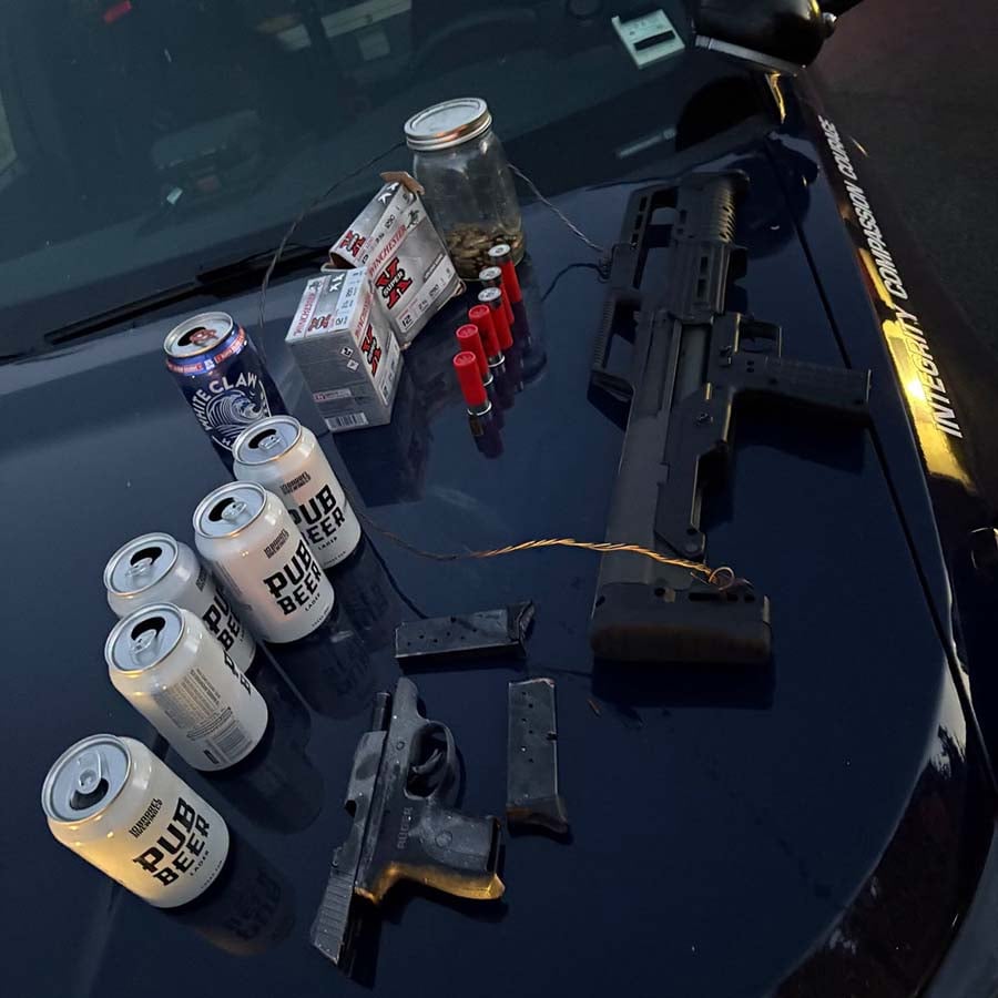 Firearms, shotgun shells, ammunition boxes and beer cans displayed on an Eugene Police patrol vehicle.