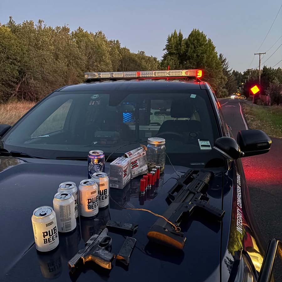 Weapons, ammunition and beer cans recovered during a Eugene arrest displayed on the hood of a police vehicle.
