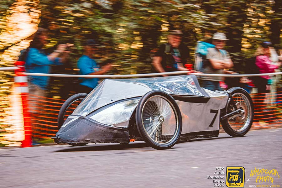 Adult racers navigating the downhill Mt. Tabor course in a handmade soapbox car during Portland’s longtime summer tradition.