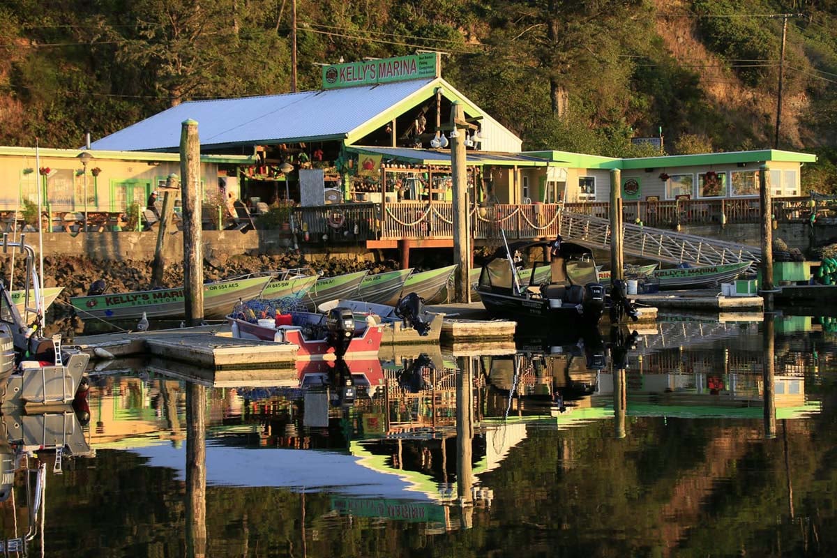 Kelly's Brighton Marina buildings and rental boats reflected in calm Nehalem Bay water
