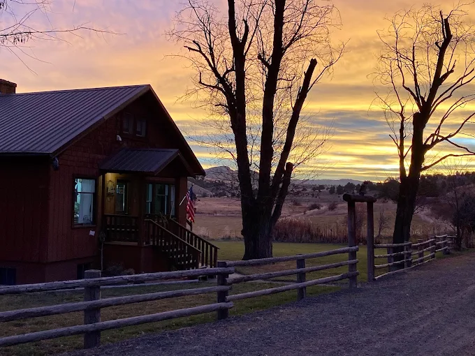 A colorful sunset behind the ranch house and split rail fence at Wilson Ranches Retreat