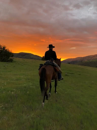 A horseback rider silhouetted against an orange high desert sunset near Fossil, Oregon
