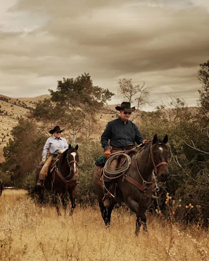 Two riders on horseback moving through high desert grassland at Wilson Ranches Retreat