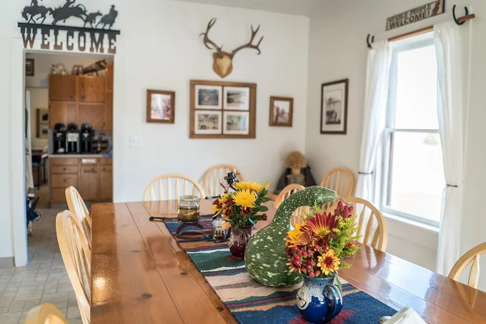 A long wooden dining table decorated with flowers inside Wilson Ranches Retreat