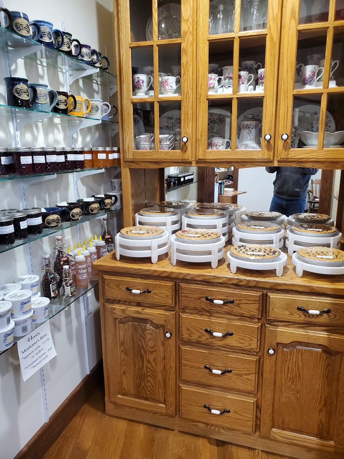 Jams, mugs, and pies displayed in and beside a wooden cabinet.