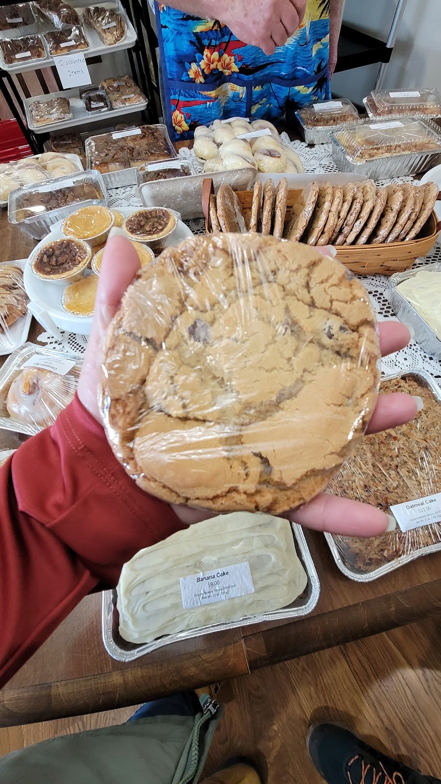 A large chocolate chip cookie photographed beside the bakery display.