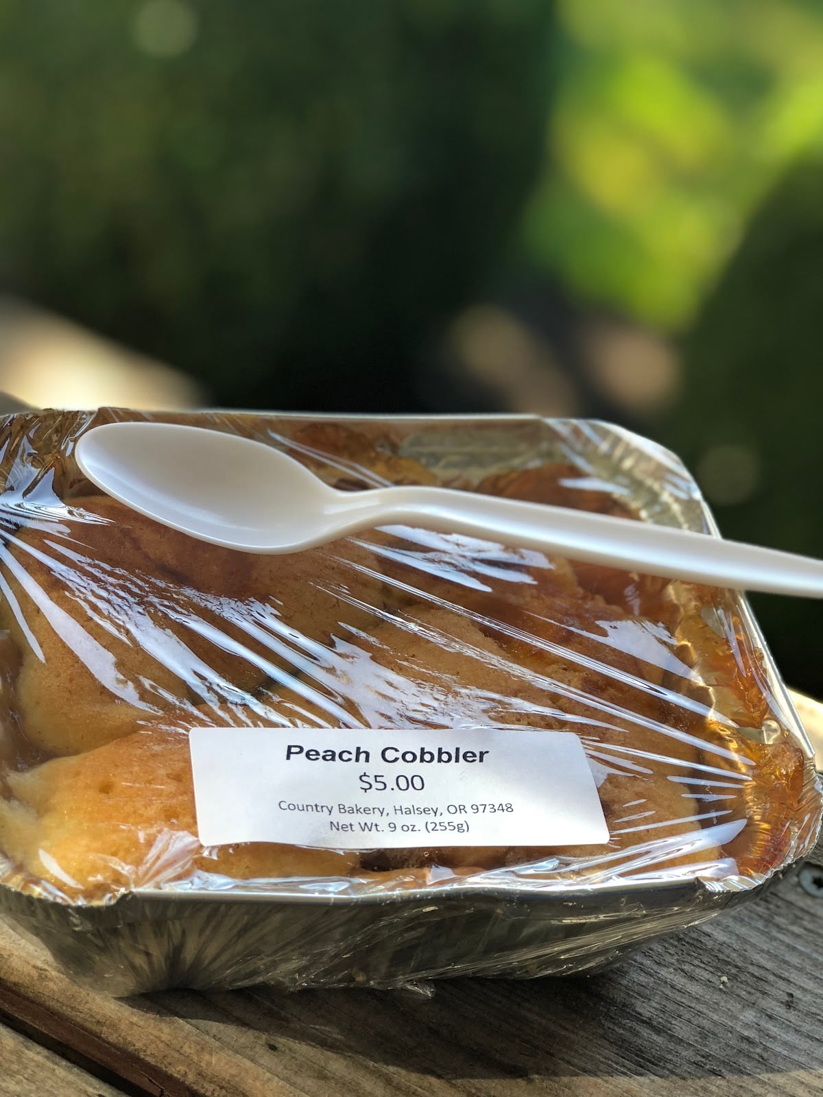 A packaged peach cobbler from Country Bakery in Halsey, with a spoon resting on top.