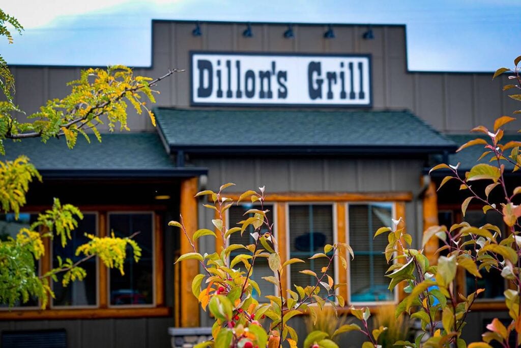 Dillon's Grill sign and restaurant exterior framed by autumn foliage in Prineville, Oregon