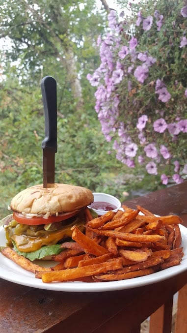 Burger and fries at Mac’s Place, with flowers beside the outdoor dining area