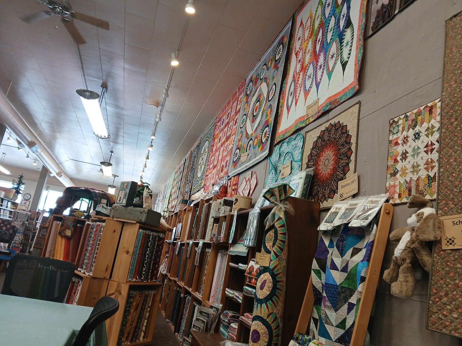 Quilts, fabric bolts, and sewing projects fill another wall of the store.
