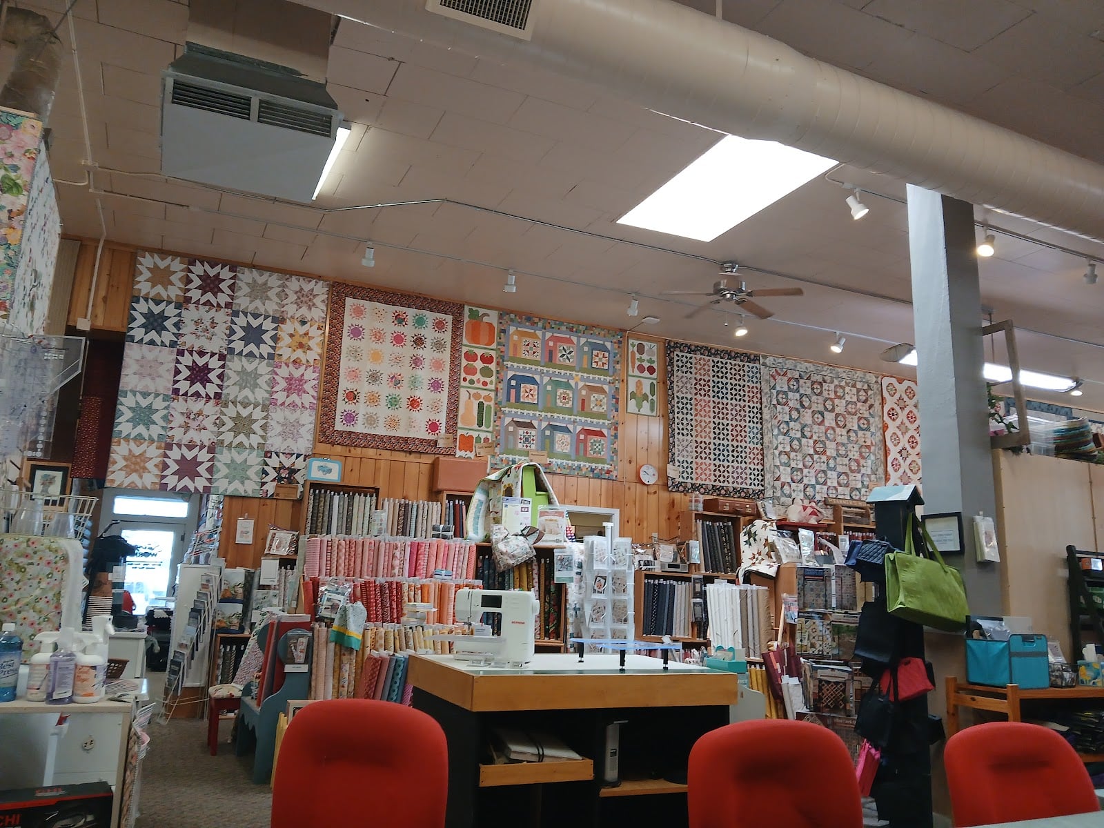 Work tables and chairs sit among the shop’s fabric and quilt displays.