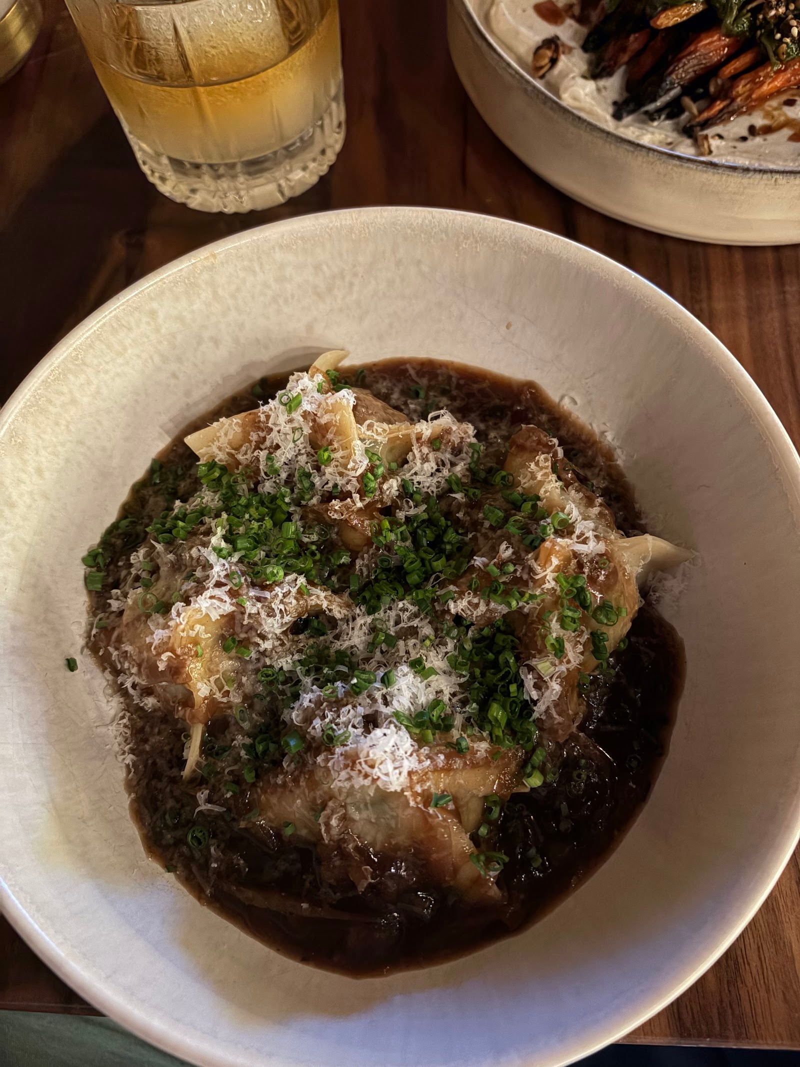 Dumplings in a dark sauce topped with grated cheese and chopped herbs at Dear Irene