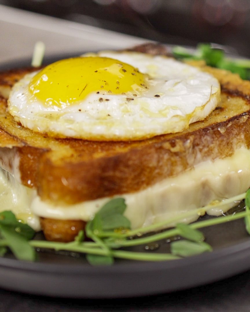 Grilled cheese with melted cheese between golden slices of bread, topped with a sunny-side-up egg at Dear Irene