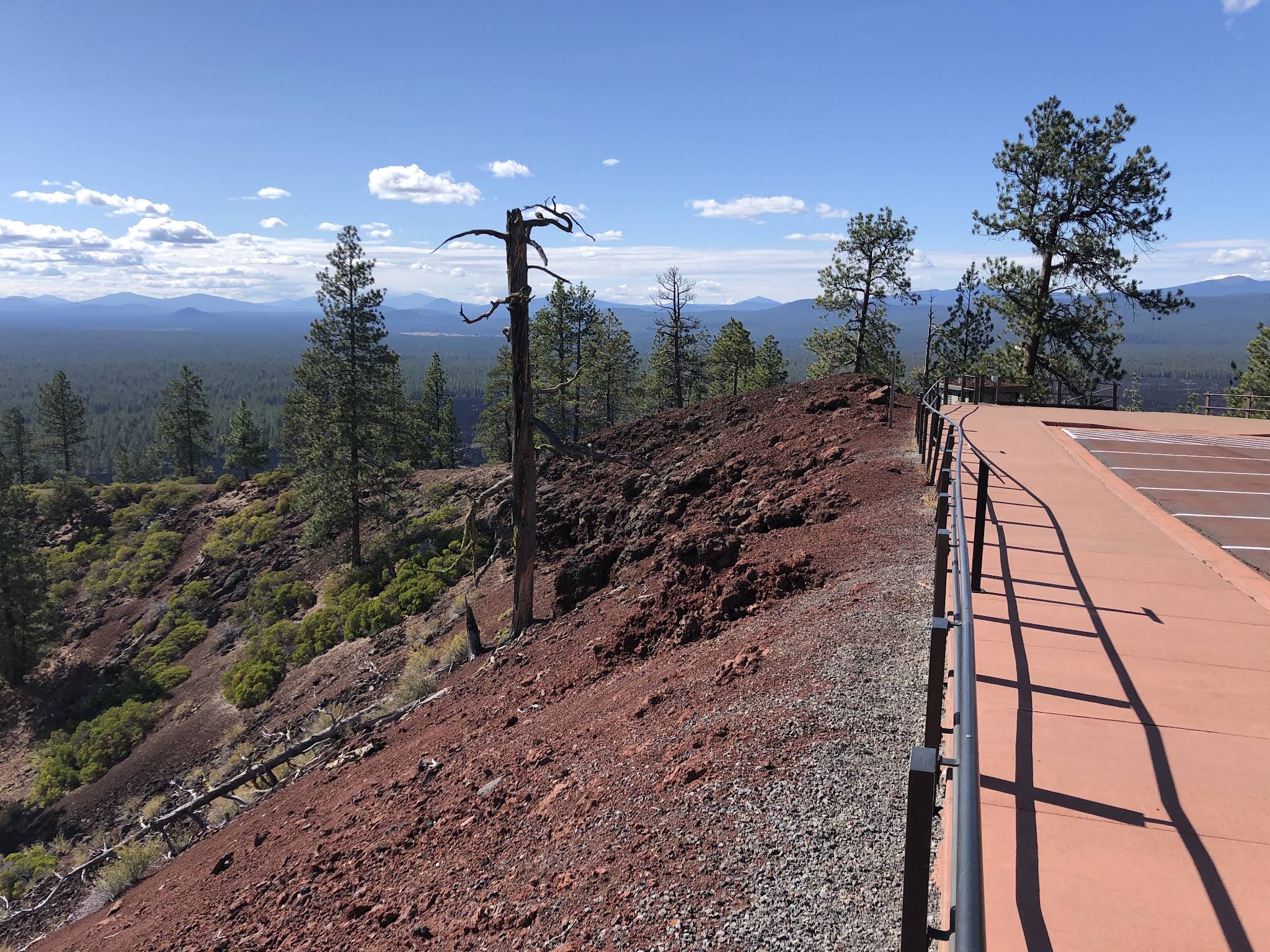 Red paved summit area at Lava Butte with scattered pines and Cascade views