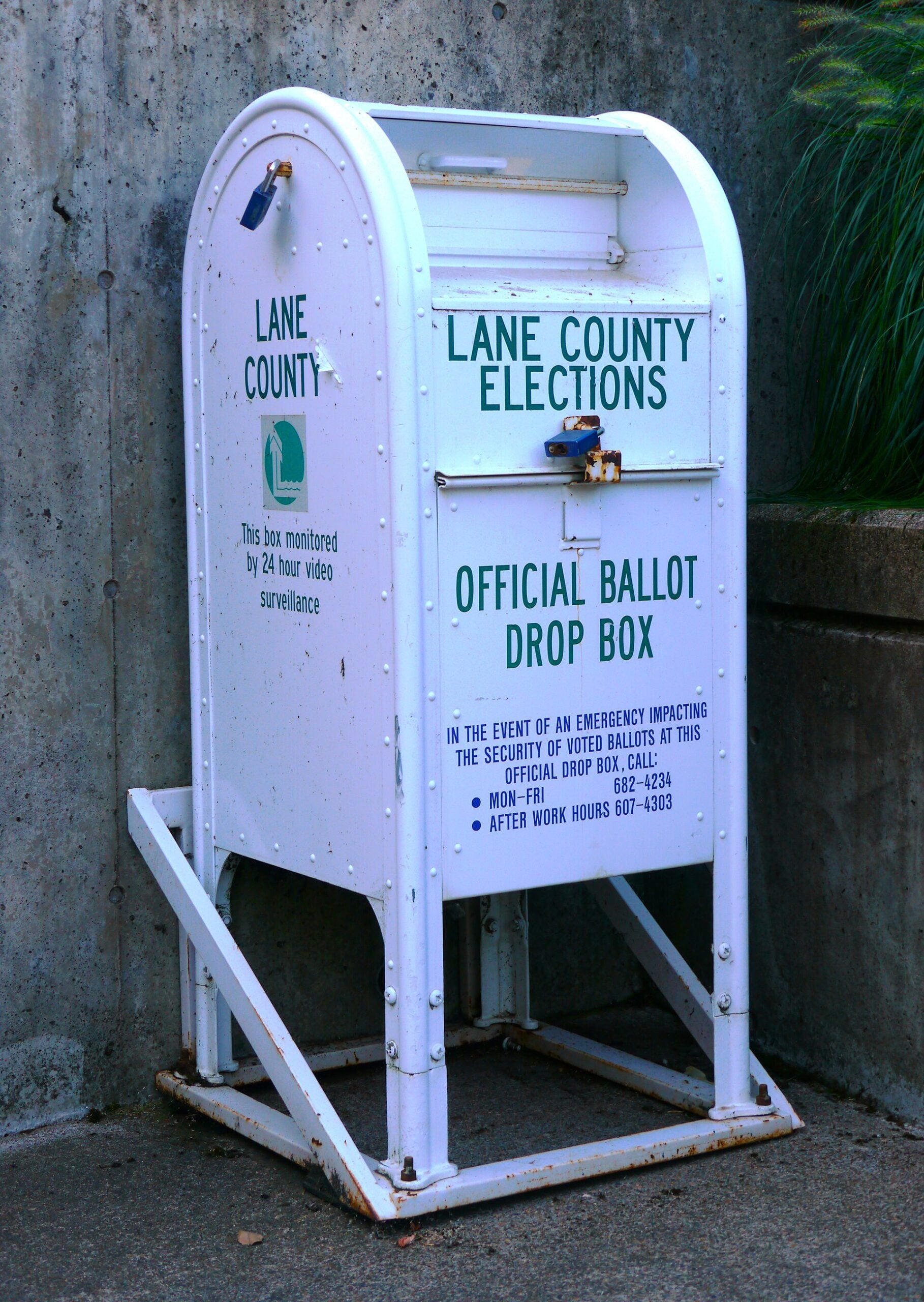 White Lane County Elections ballot drop box beside concrete steps on the University of Oregon campus
