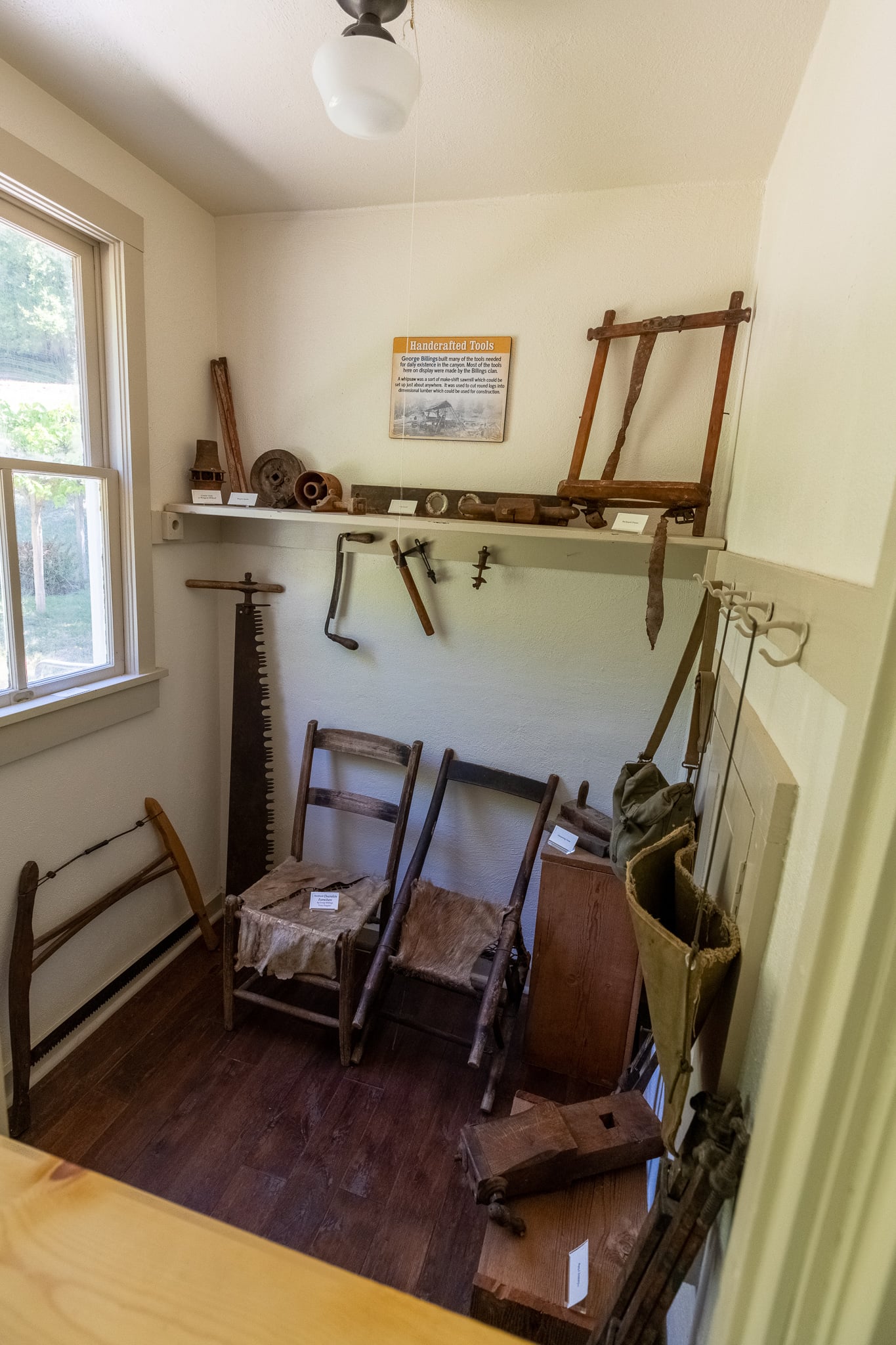 Long handled tools and wooden equipment displayed beneath windows inside Rogue River Ranch