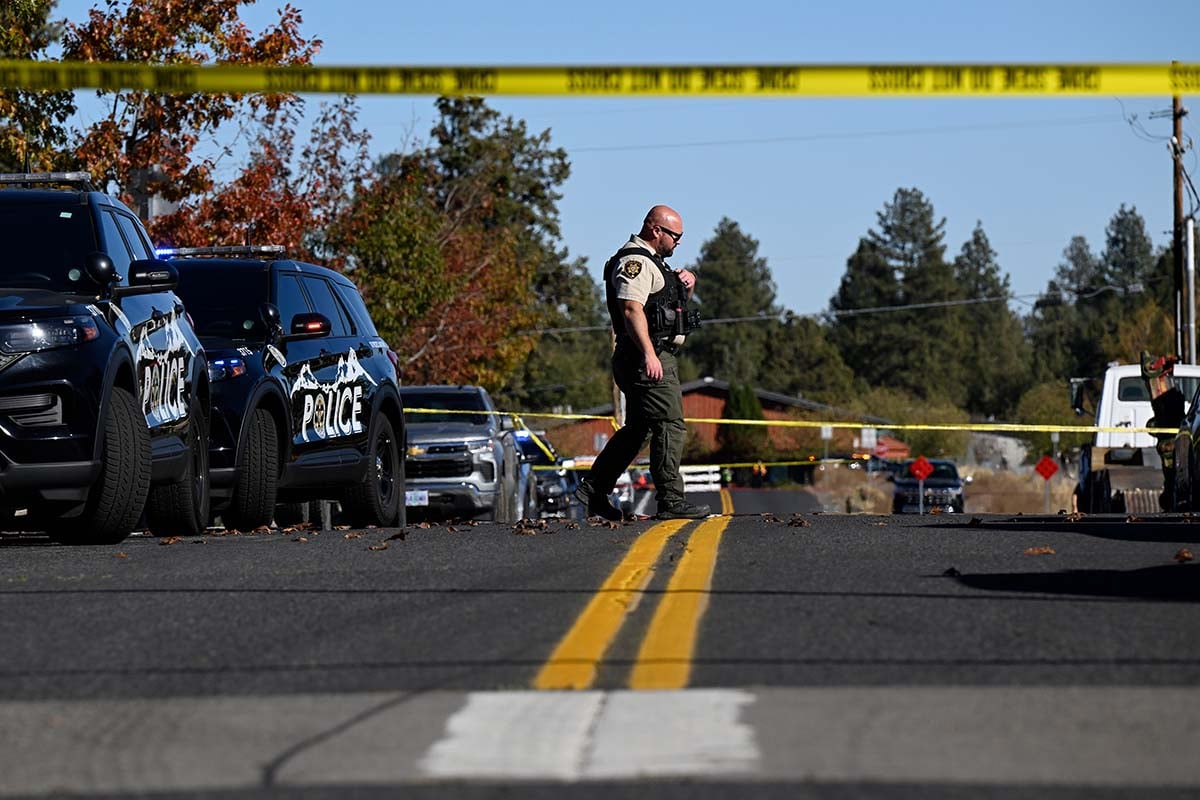 A sheriff’s deputy crosses a street lined with police vehicles and yellow police tape near Silver Rail Elementary School in Bend, Oregon.