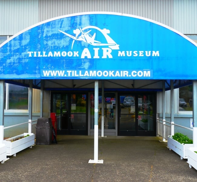 Blue Tillamook Air Museum entrance canopy with an aircraft graphic above the doors