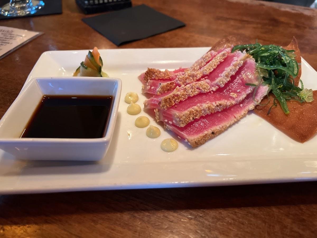 Sesame-crusted seared ahi slices with greens and dipping sauce on a rectangular white plate at Vault 244.